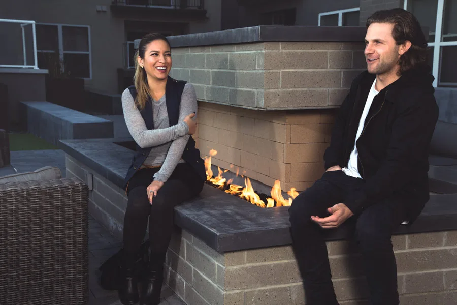 Two residents talking beside a built-in fire feature in a rooftop courtyard