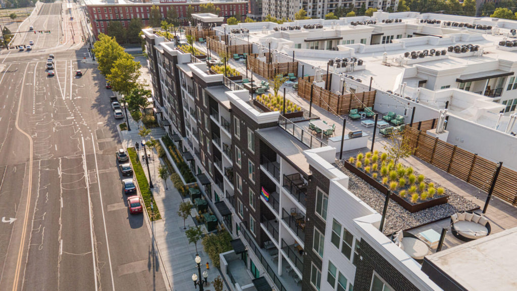 Aerial view of a multifamily rooftop terrace with planting, dining, and lounge areas