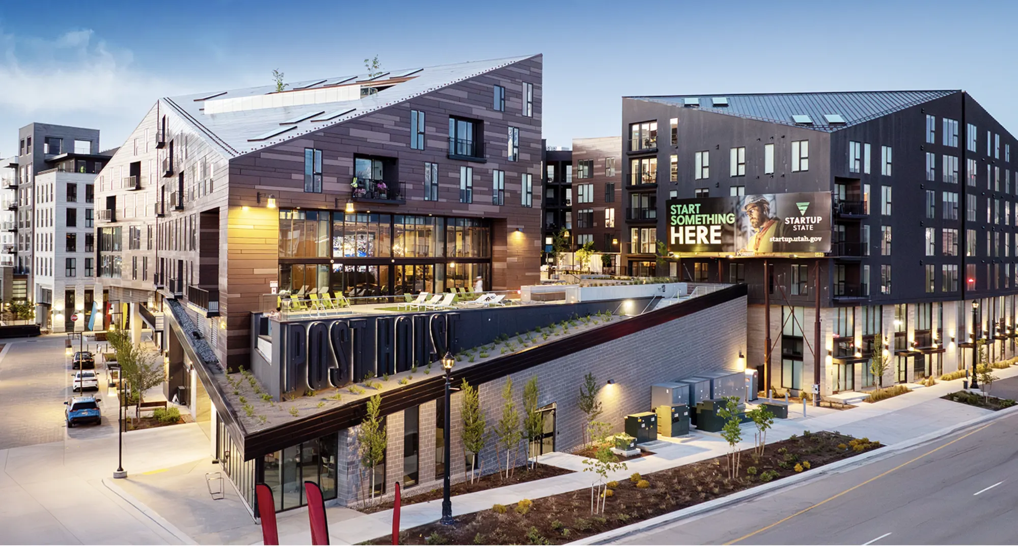 Post House mixed-use district at dusk: the POST HOUSE rooftop signage, amenity deck, and surrounding buildings.